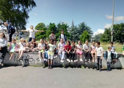 Ferienspielgruppe draußen auf einer kleinen Mauer